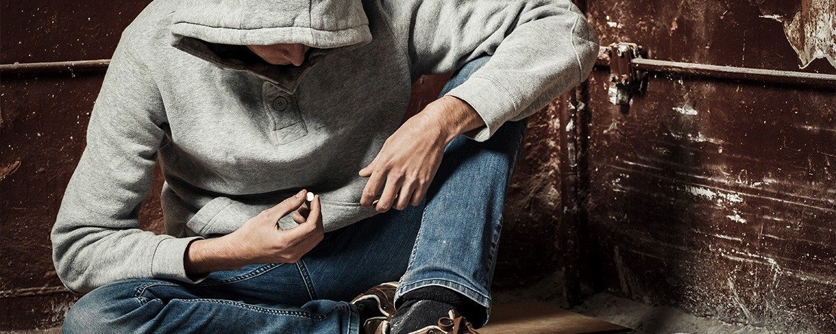 Man sitting in corner taking a pill alone