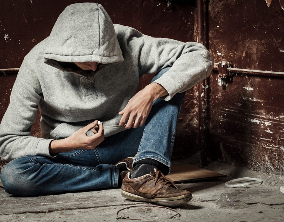 Man sitting in corner taking a pill alone