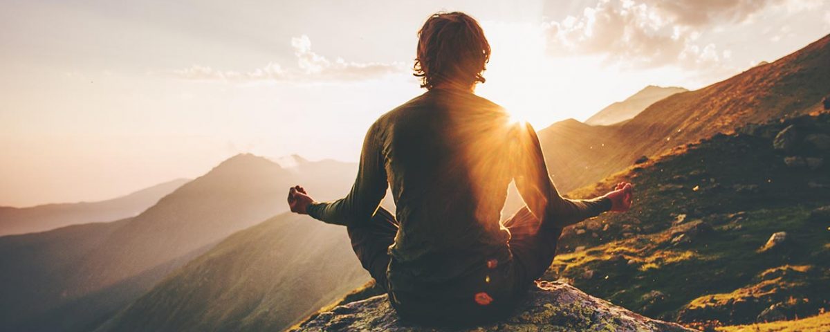 man meditating on mountain