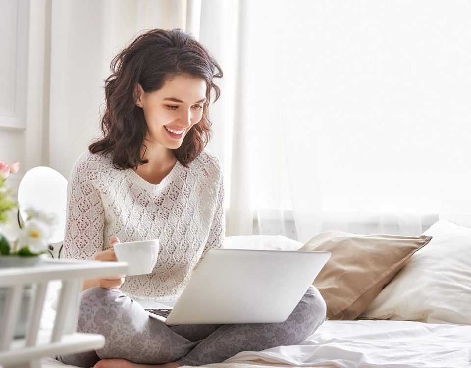 Woman drinking coffee and looking at her laptop